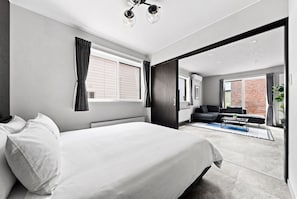 Quarto moderno com uma cama grande, um sofá e vista para o exterior.