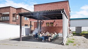 An outdoor patio area with a covered seating arrangement and a grill. - BRIC (Asahikawa)