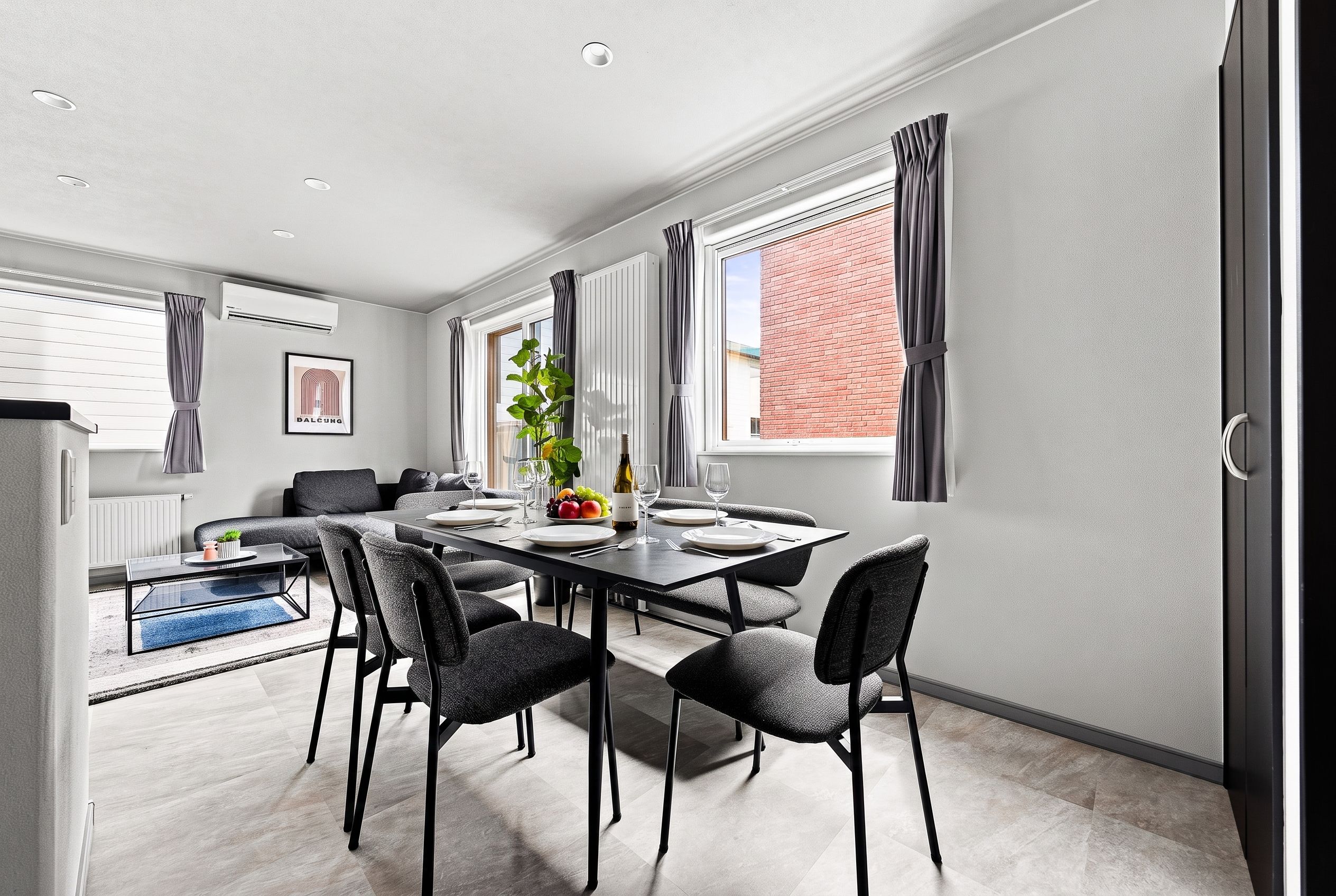 A modern dining area with a rectangular table, six chairs, and a potted plant.