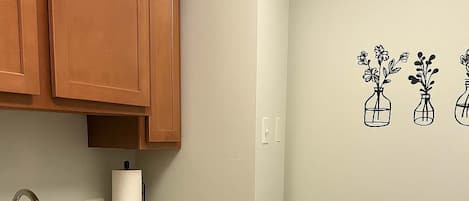 A kitchen with wooden cabinets, a granite countertop, a stainless steel sink, and a black trash bin.