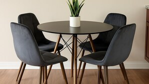 Een ronde tafel met vier stoelen, een bloempot en twee wandlampen.