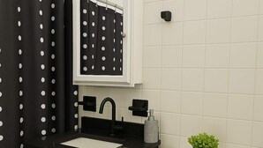 Ein Badezimmer mit schwarzem Waschtisch, weißem Waschbecken und Toilette.