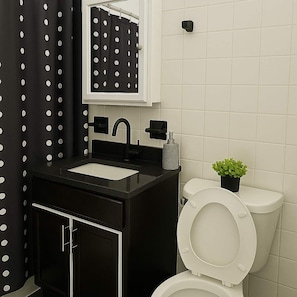 A bathroom with a black vanity, white sink, and a toilet. - Chic 2BR Haven Near Irving Park (Chicago)