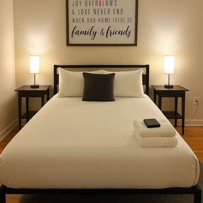 A neatly made bed with a pillow, two bedside lamps, and a framed inspirational quote on the wall. - Chic 2BR Haven Near Irving Park (Chicago)