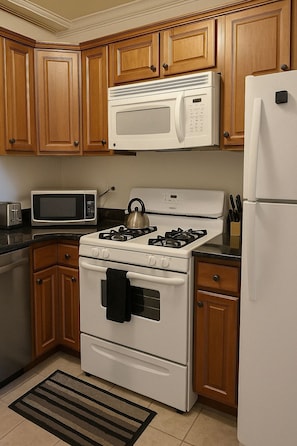 A kitchen with wooden cabinets, a stove, a microwave, and a refrigerator. - Chic 2BR Haven Near Irving Park (Chicago)