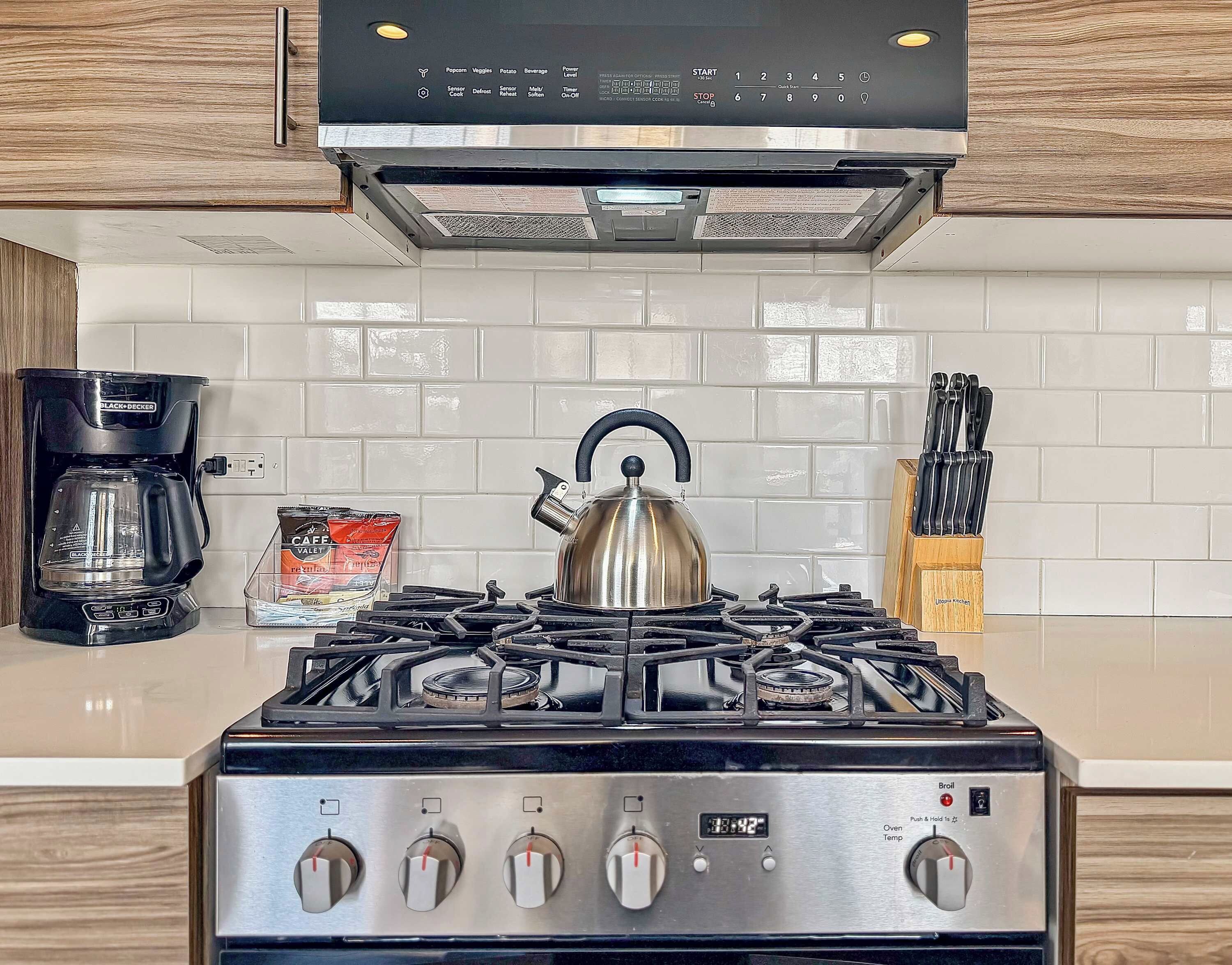 Une cuisine équipée d’une cuisinière à gaz, d’une bouilloire, d’une machine à café et d’un bloc à couteaux.
