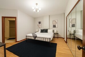 A modern bedroom with a bed, bedside tables, a mirror, and artwork on the walls.