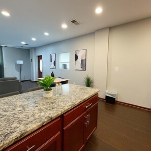 Une cuisine moderne dotée de plans de travail en granit, d’un four encastré et d’un petit îlot central agrémenté d’une plante.