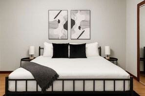 Um quarto moderno com uma cama, duas mesas de cabeceira e arte abstrata na parede.