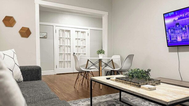 A modern living room with a grey sofa, a coffee table, and a TV mounted on the wall.
