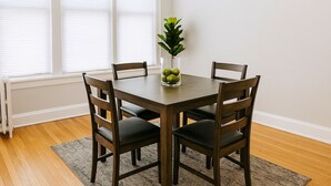 A dining table with four chairs, a vase with green apples, and a plant. - Cozy 1BR in Walkable Area (Chicago)