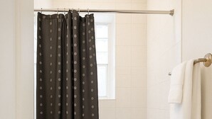 A bathroom with a bathtub, a shower curtain, a towel rack, and a black mat. - Cozy 1BR in Walkable Area (Chicago)