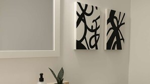 Un baño con lavamanos, grifo, dispensador de jabón y una planta en maceta.