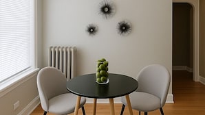 A room with a round table, two chairs, a radiator, and wall art. - Charming 1BR in Old Irving (Chicago)
