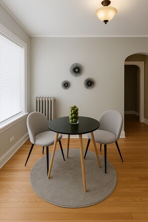Een kamer met een ronde tafel, twee stoelen, een radiator en decoratie aan de muur.