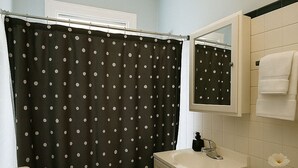 A bathroom with a toilet, sink, and shower curtain. - Charming 1BR in Old Irving (Chicago)