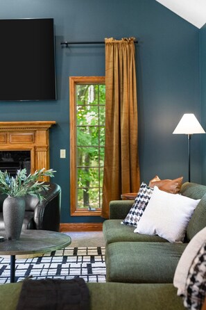 A living room with a fireplace, a sofa, a coffee table, and a television. - Heated Pool | Sauna | Hot Tub | Theater | Games (Kalkaska)