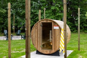 A wooden sauna structure with a door, a warning sign, and a towel hanging on the side. - Heated Pool | Sauna | Hot Tub | Theater | Games (Kalkaska)