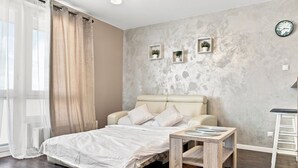 Un dormitorio con cama, mesita de noche y un reloj de pared.