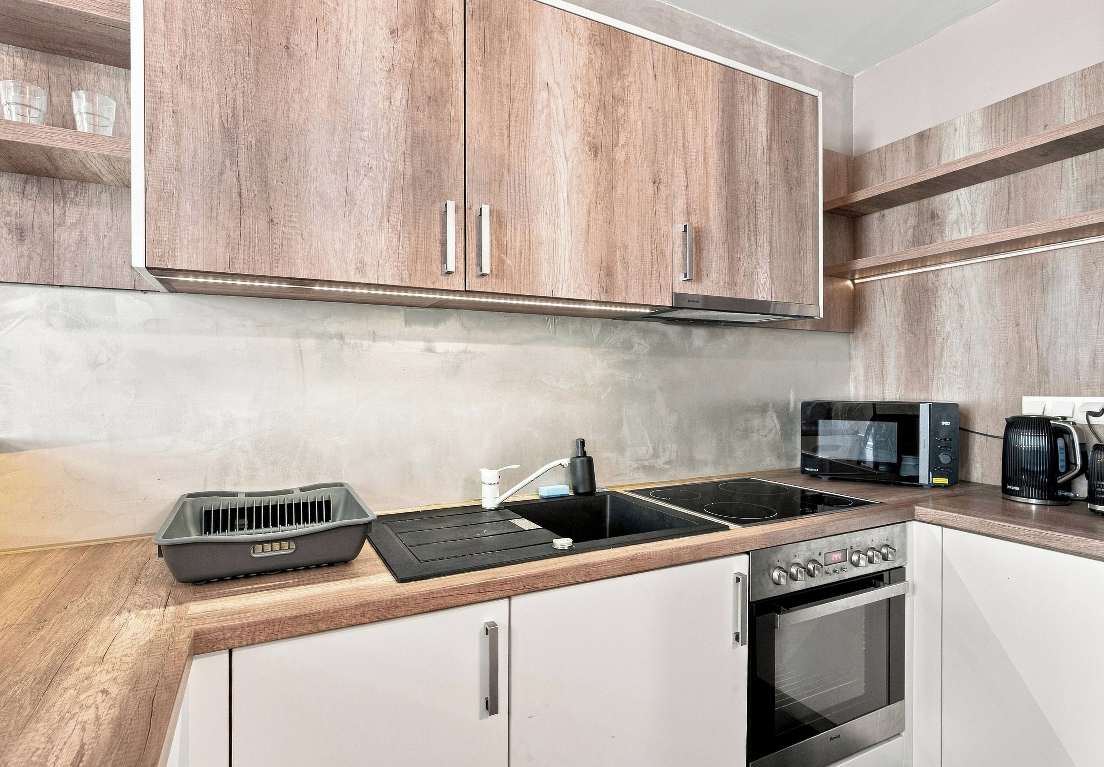 Una cocina moderna con armarios de madera, un microondas integrado, estufa y lavavajillas.