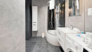 Un baño moderno con ducha de vidrio, un lavamanos blanco y un espejo.