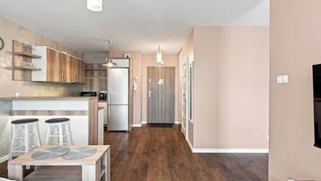 A modern kitchen with wooden cabinets, a refrigerator, and a dining area with stools.