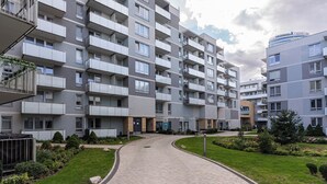 Un edificio residencial de varios pisos con balcones, un camino pavimentado y jardines ajardinados.