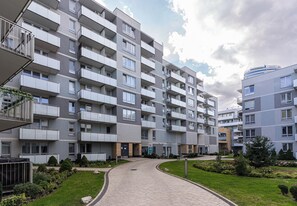 Een meerlaags woongebouw met balkons, een verharde oprit en aangelegde tuinen.