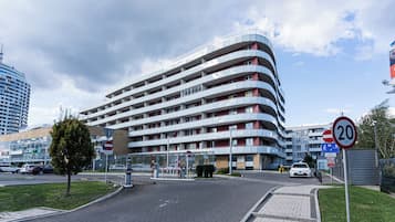 Un hotel de varios pisos con fachada curva, un paso de peatones y una señal de límite de velocidad.
