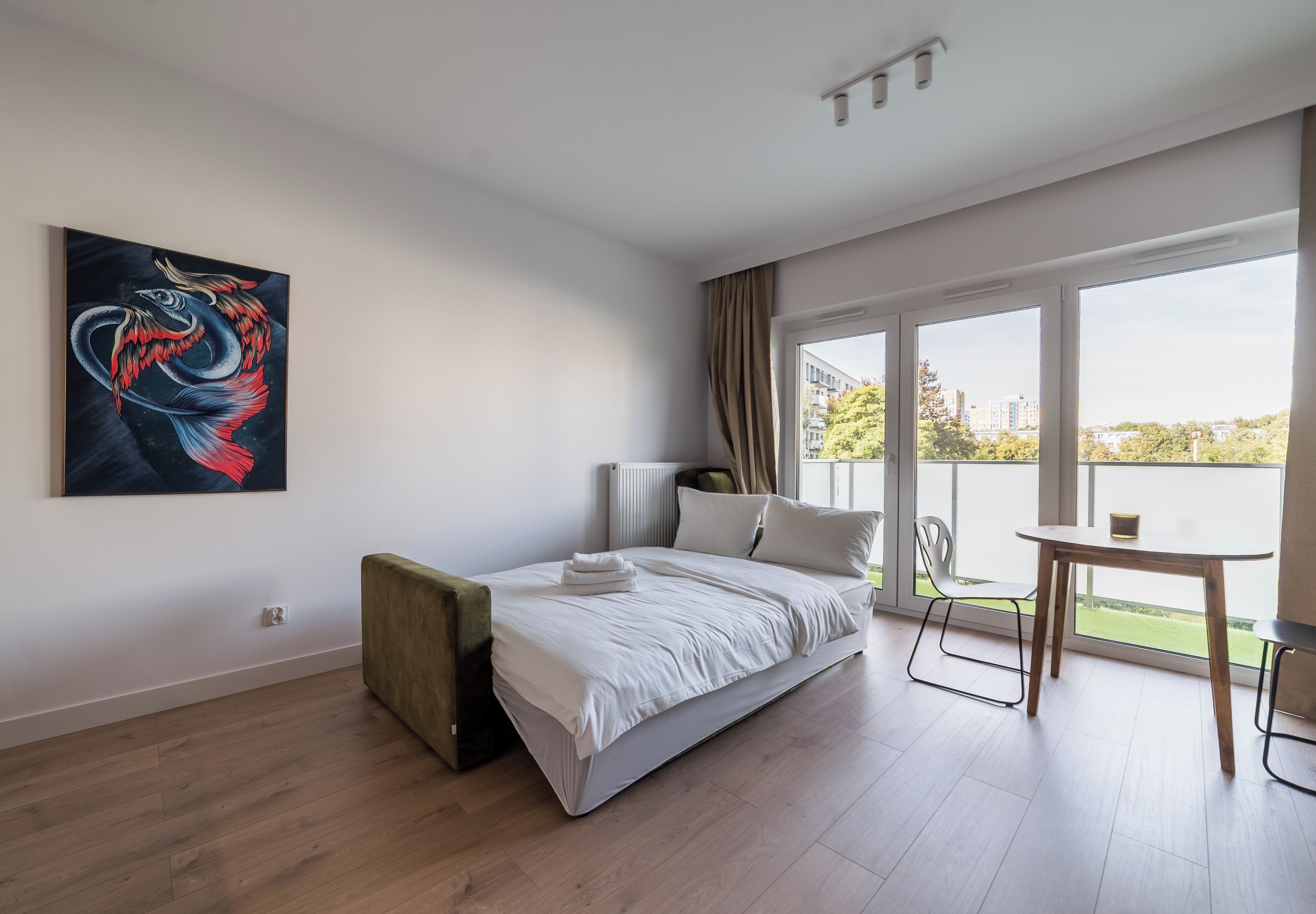 Quarto moderno com cama, pintura, vista da cidade e varanda.