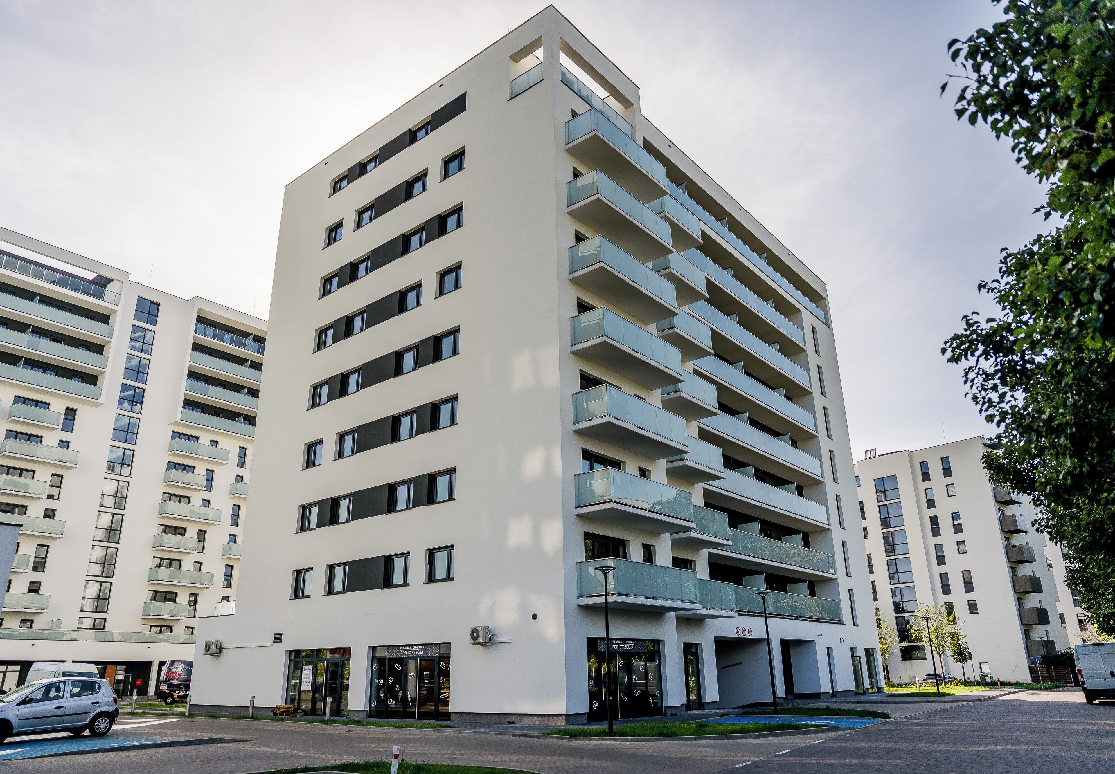 A multi-story residential building with balconies, a ground-level entrance, and a visible storefront.