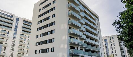 Un edificio residencial de varios pisos con balcones, acceso a nivel de calle y una fachada comercial visible.