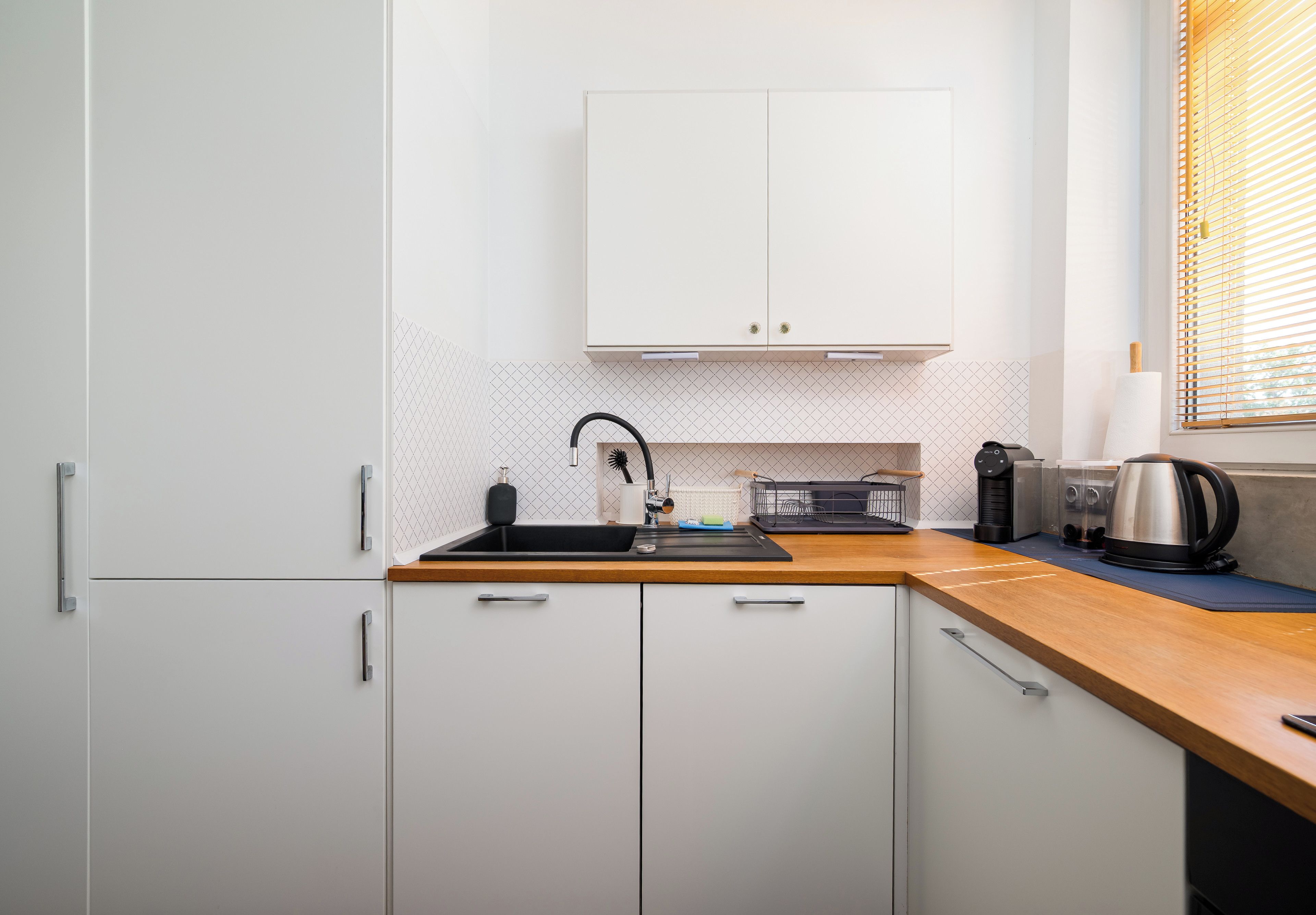 A compact kitchen with a sink, cabinets, and a coffee maker.