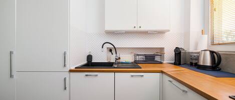 A compact kitchen with a sink, cabinets, and a coffee maker.