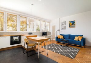 Eine moderne Küche mit Essbereich, einem blauen Sofa und Bildern an der Wand.