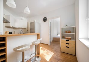 Eine moderne Küche mit einer zentralen Kochinsel, Barhocker, einem Kühlschrank und einer Uhr an der Wand.