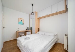 Ein Schlafzimmer mit Bett, Schreibtisch, Stuhl, Kleiderschrank und einem Bild an der Wand.