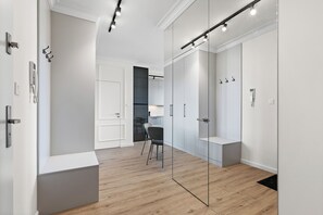Ein modernes Interieur mit Holzboden, weißen Wänden und einer Glastrennwand. Ein Stuhl und ein kleiner Tisch befinden sich in der Mitte.