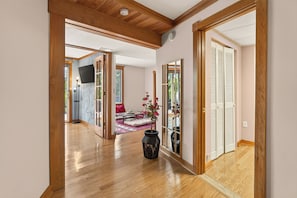 Un couloir avec un plancher en bois, un miroir et une plante en pot.