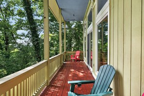 Une véranda couverte avec un plancher en bois, une balustrade et deux fauteuils Adirondack.