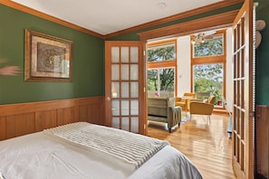 Une chambre à coucher avec un lit, une porte donnant sur un balcon et un tableau encadré au mur.