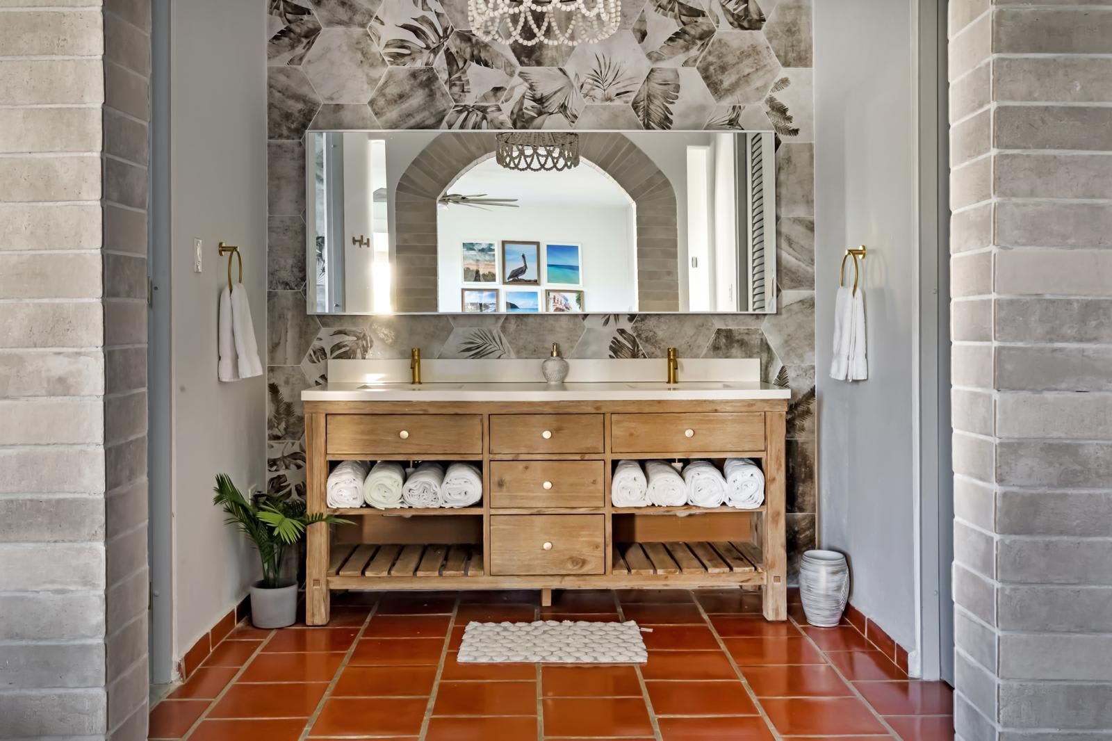 A bathroom with a wooden vanity, a large mirror, and a tiled floor.
