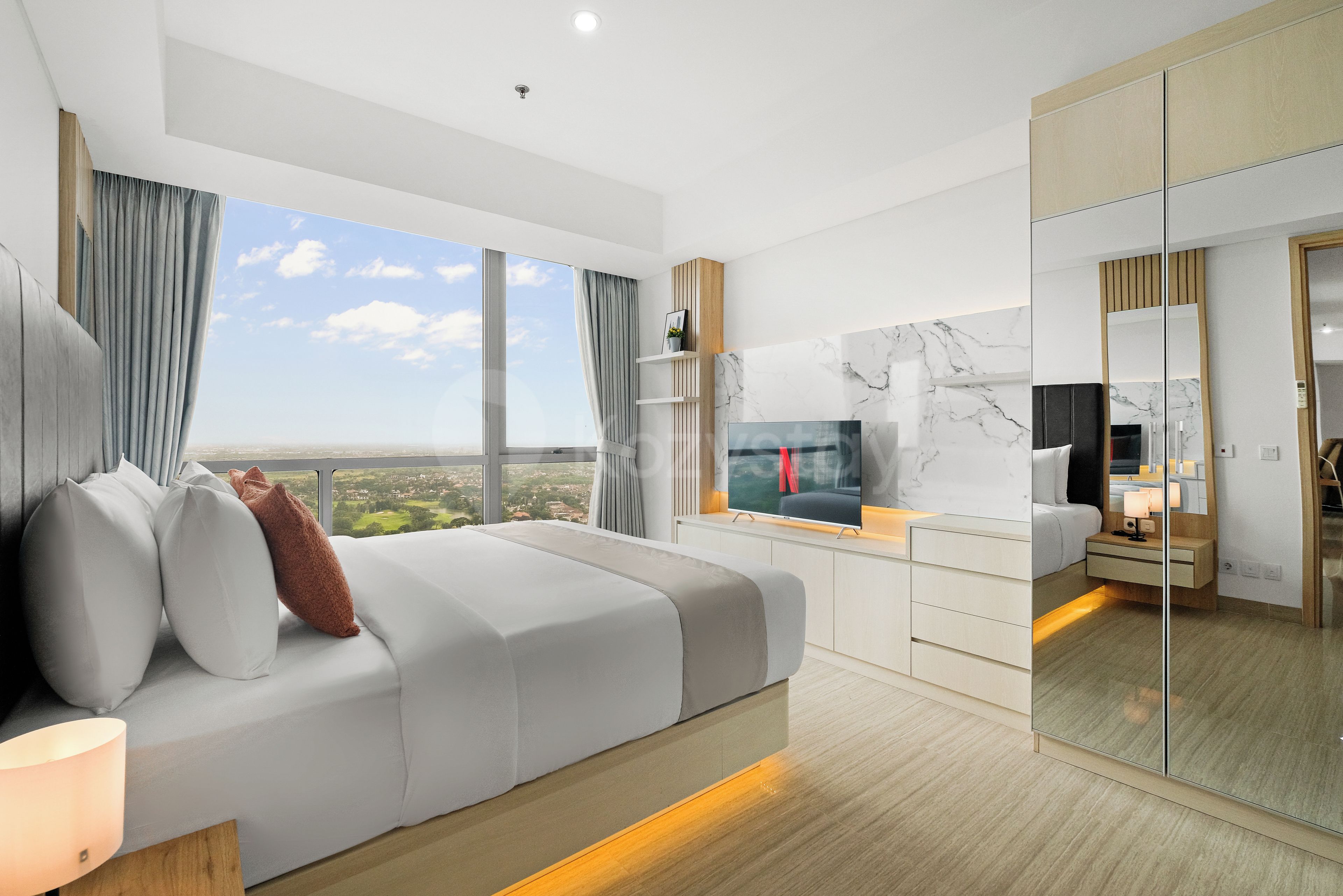 Un dormitorio moderno con una cama grande, televisión y vista a la ciudad.