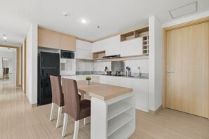 Eine moderne Küche mit Essbereich, weißen Schränken, einem schwarzen Kühlschrank und einer Holztür.