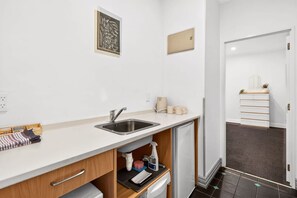 A modern kitchen with a sink, countertop, and a small refrigerator. - Contemporary 1BR in the City Centre Zodiak Stays (Auckland)