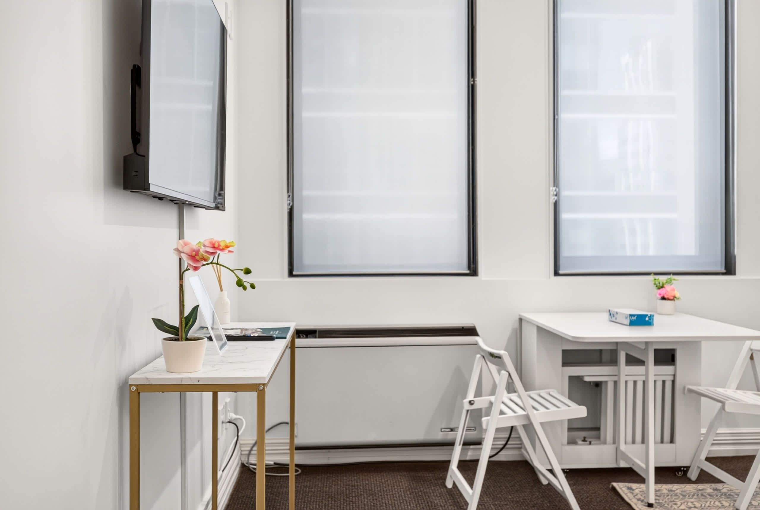 Un espace de bureau moderne comprenant un bureau, une chaise, un radiateur et de grandes fenêtres.