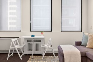 A modern living room with a white desk, two white chairs, a grey sofa, and a patterned rug. - Contemporary 1BR in the City Centre Zodiak Stays (Auckland)