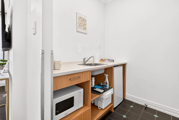 A compact kitchenette with a microwave, sink, and storage cabinets. - Inviting 1BR Escape in Auckland CBD Zodiak Stays (Auckland)