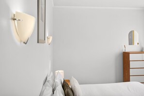 Ein Schlafzimmer mit einem Bett, einem Nachttisch, einer Kommode und Wandleuchten.