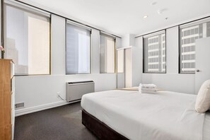A hotel room with a large bed, a radiator, and a window with blinds. - Inviting 1BR Escape in Auckland CBD Zodiak Stays (Auckland)